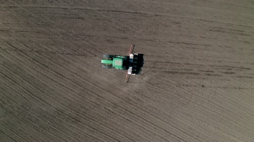 Feld mit malerischen Hügeln und einem fahrenden Traktor