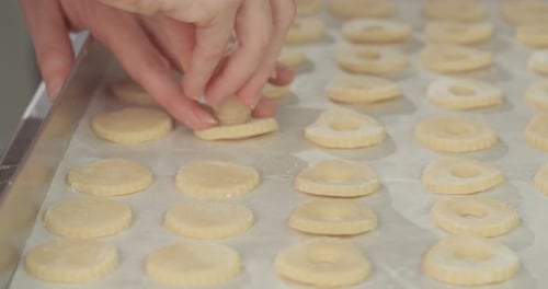 Baker preparing butter cookies with strawberry jam and powdered sugar