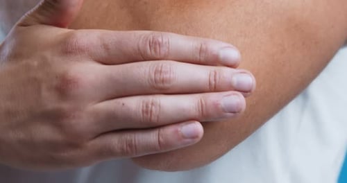 Hombre aplicándose ungüento en el codo para tratar la piel seca, de cerca