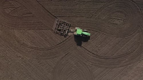 Agricultural green big tractor in the field plows with a plow