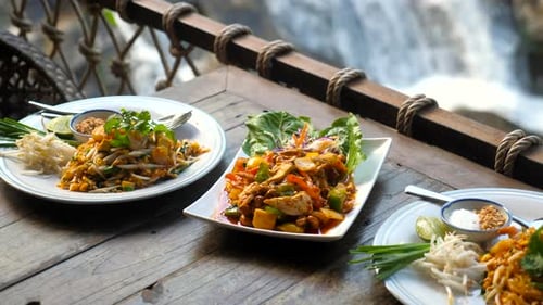 Traditional Thai Food in Outdoor Cafe with Nature Waterfall Background
