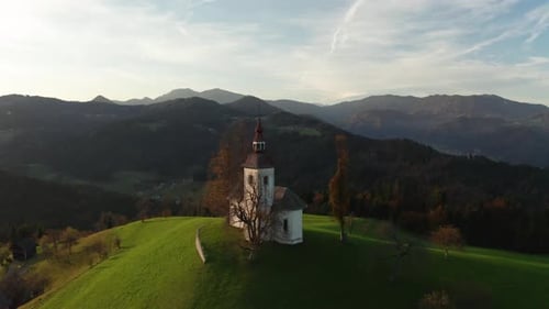 Aerial View of Hills, Colorful Forest and Sv Tomaz Church. Sunset in Slovenia in Autumn