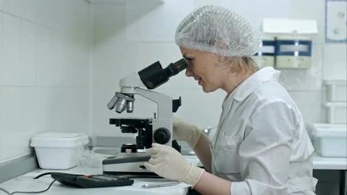 Scientist Examining Sample Through Microscope in Lab