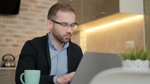 Man Working on Laptop at Home Kitchen Table