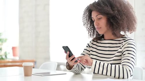 Woman Using Mobile Phone Indoors at Bright Table