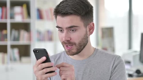 Excited Man Celebrates Good News on Smartphone