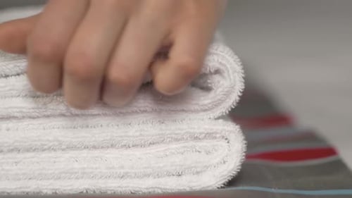 Close-up of Hands Putting Stack of Fresh White Bath Towels on the Bed Sheet. Room Service Maid