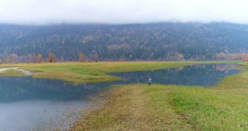 Lone Figure by Lake in Rural Landscape