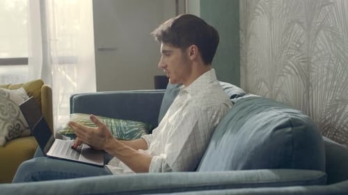Young Adult Man Using Laptop on Sofa