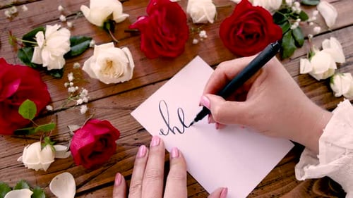 Writing HELLO on a card near flowers close up