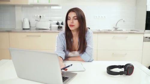 Woman Studying and Taking Notes in Kitchen