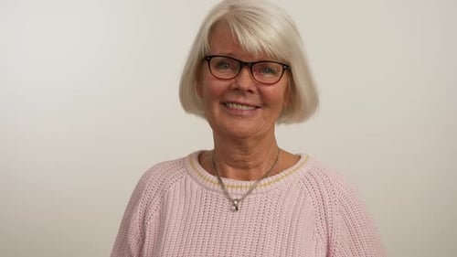 Smiling Senior Woman Puts on Reading Glasses