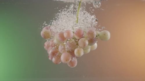 Branch of grapes falling into transparent water