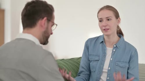 Femme heureuse ayant une conversation avec un homme sur un canapé