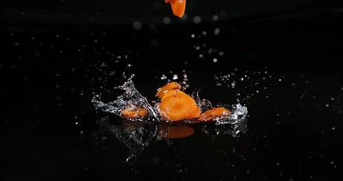 Karotten, Daucus Carota, auf Wasser fallendes Gemüse vor schwarzem Hintergrund, Zeitlupe 4k
