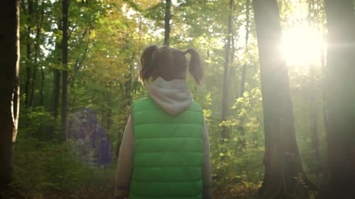 Little Girl Walking Through Tall Trees in Forest
