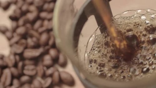 Verser du café frais dans une casserole avec fond de grains de café