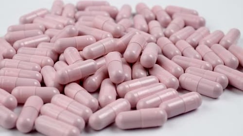 Close up of the rotation soft pink pills or capsules on white background