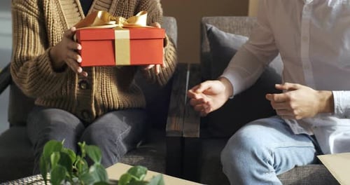 Red Gift Box Presented Between a Loving Couple