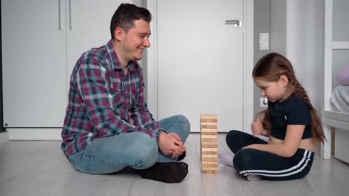 Father and daughter. They look at the camera and speak to the camera. They are playing in the tower