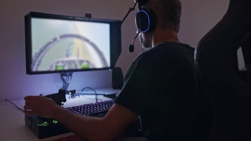 Man playing a flight simulator on the computer, wearing a headset