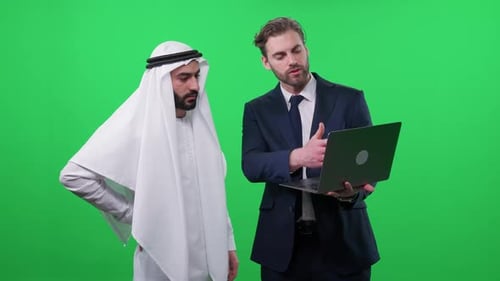 Businessman Showing Laptop to Man in Traditional Dress