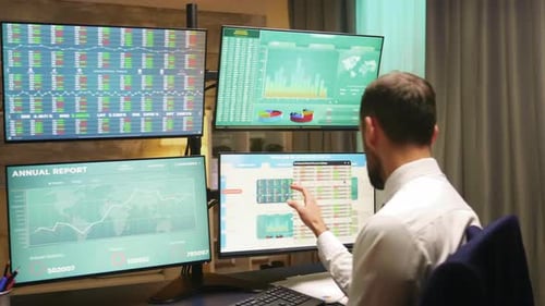 Businessman in Home Office at Night Checking the Stock Market