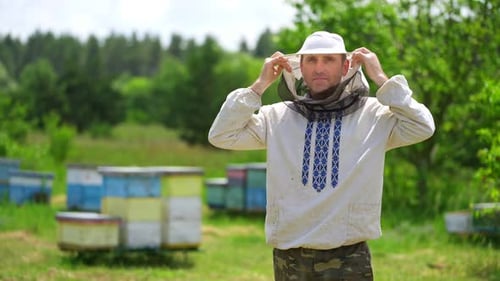 Beekeeper Adjusts Protective Netting Near Beehives