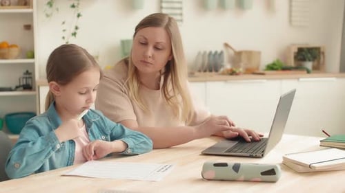 Woman Helping Girl with Homework in Kitchen