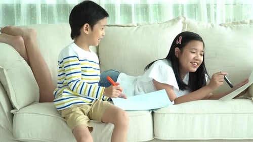 Children Drawing Together on Cream Couch