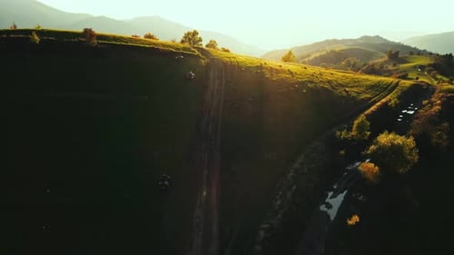 ATVs Ride on Green Hills at Sunrise