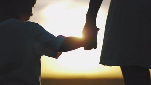 Child and Woman Holding Hands at Sunset