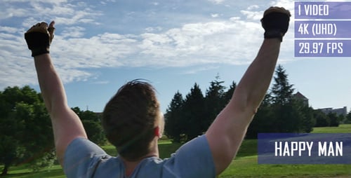 Man Celebrates Success With Arms Raised in Park