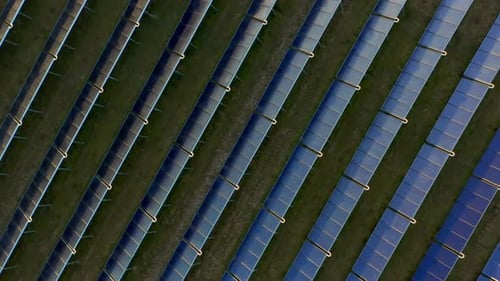 Drohne über blauen Sonnenkollektoren in Reihe im Grasfeld