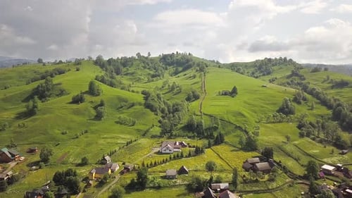 Aerial view of a small village between green summer hills in ukrainian Carpathian mountains