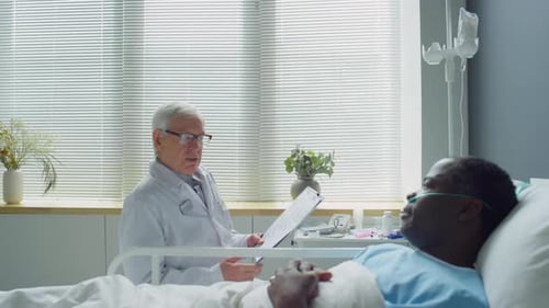 Senior Doctor Visiting Patient in Hospital Ward