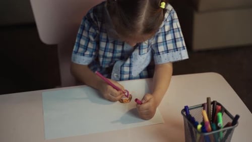 Child Drawing at Table with Colorful Markers