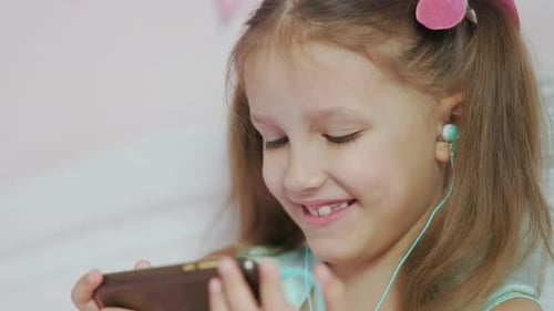 Smiling Girl Using Smartphone With Headphones Indoors