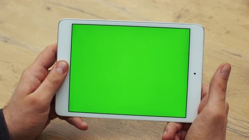 Man Using Horizontal Tablet with Green Screen. Close-up Shot of Man's Hands with Tablet. Chroma Key
