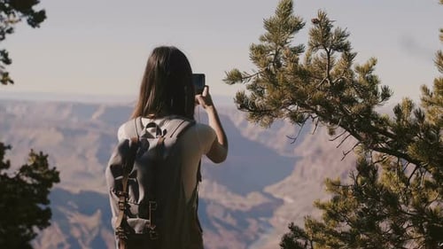 Back View Happy Tourist Woman Hiking, Taking Smartphone Photo of Amazing Grand Canyon National Park