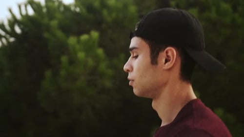 Man Walking Outdoors in Park Wearing Baseball Cap