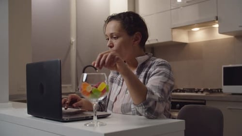 Woman Uses Laptop and Eats Gummy Candies