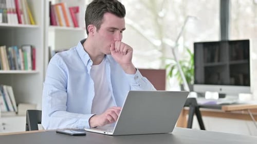 Adult Man Coughing While Using Laptop in Office