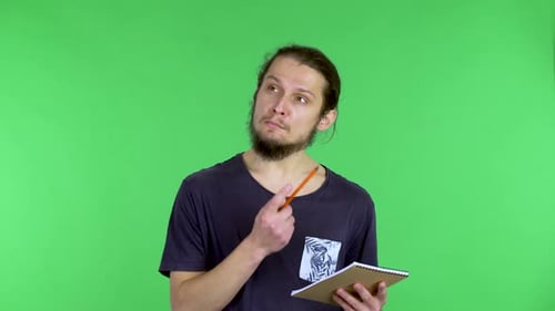 A Portrait of a Caucasian Man Who Thinks About Something Then Writes Something Down in a Notebook