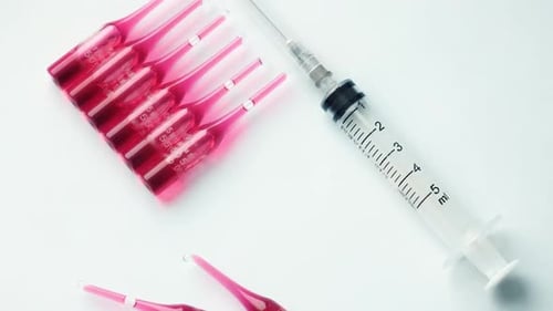 Syringe with Ampoules and Red Medicine Lie on a Pastel Blue Background