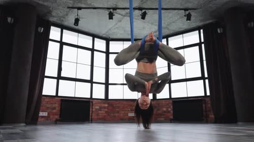 Woman Practicing Aerial Yoga Upside Down