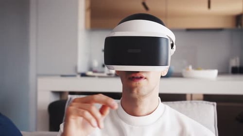 Young Caucasian Man Using Virtual Glasses And Working At Home With Cyber Space Swiping with Hands