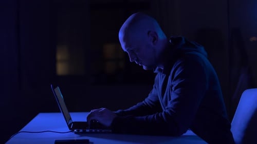 Man Working on Laptop at Night in Blue Light