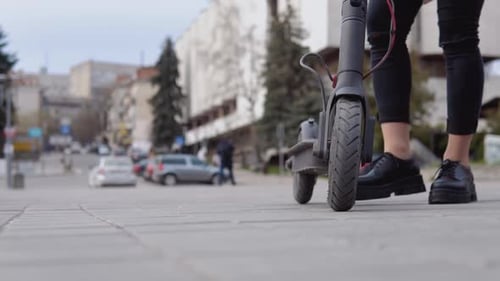 Woman Rides Electric Scooter on Sidewalk
