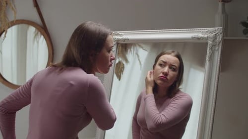 Woman Applying Makeup in Front of Mirror